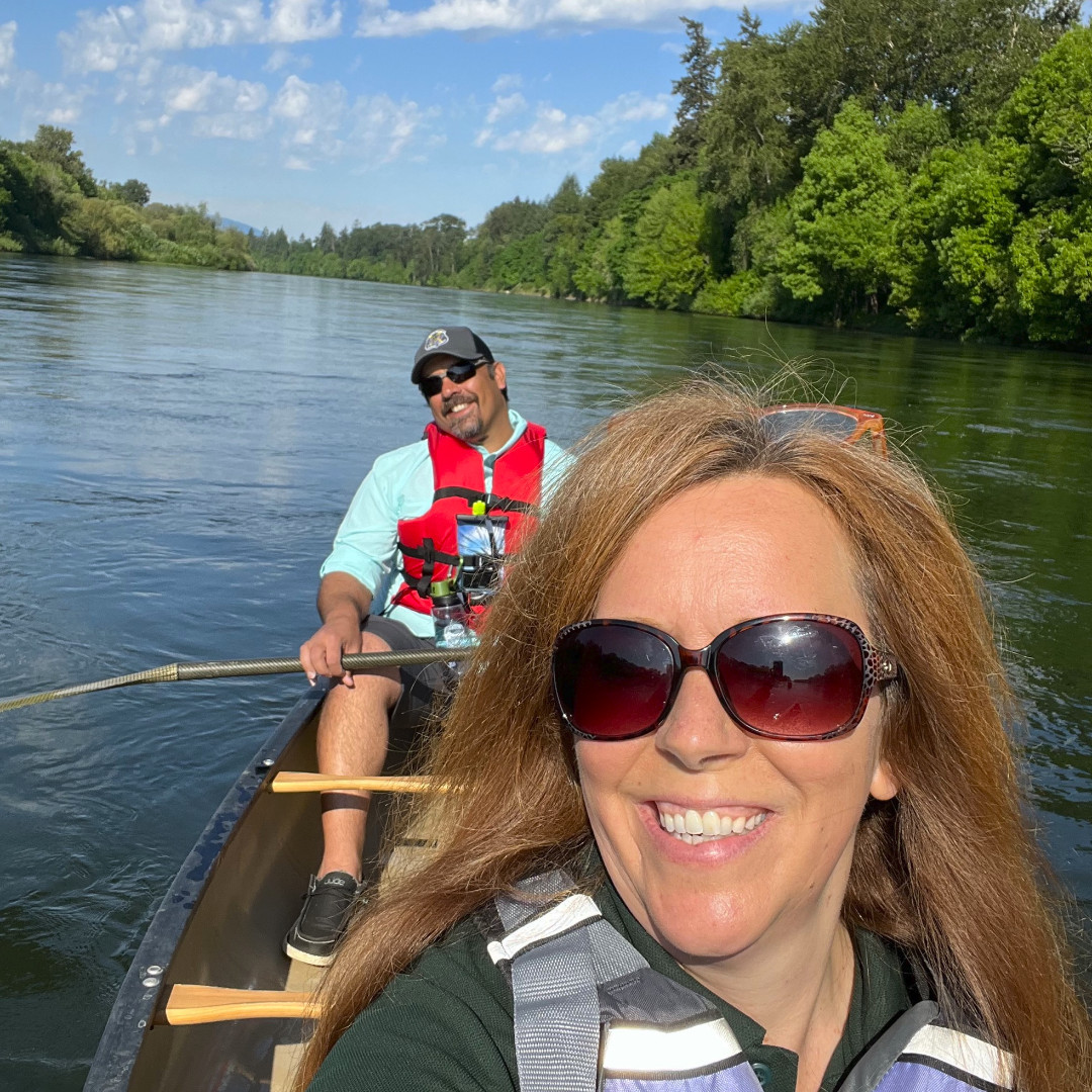 Director Lisa Sumption and Deputy Director J.R. Collier in a canoe on the Willamette River, wearing life jackets.